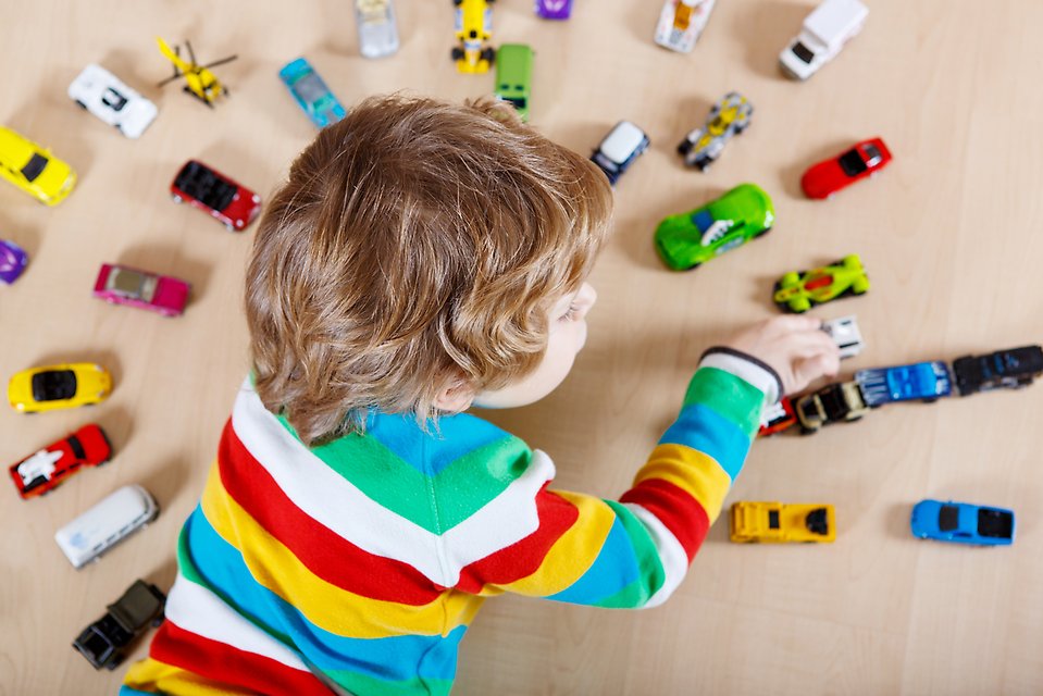 Ett barn leker med bilar på golvet