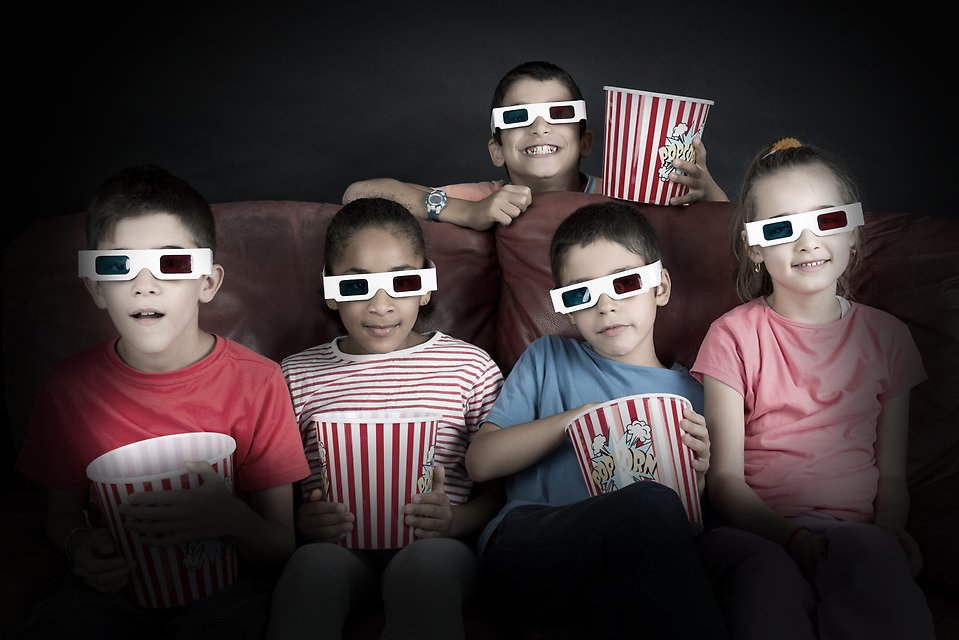 Barn med popcornskålar och 3D-glasögon