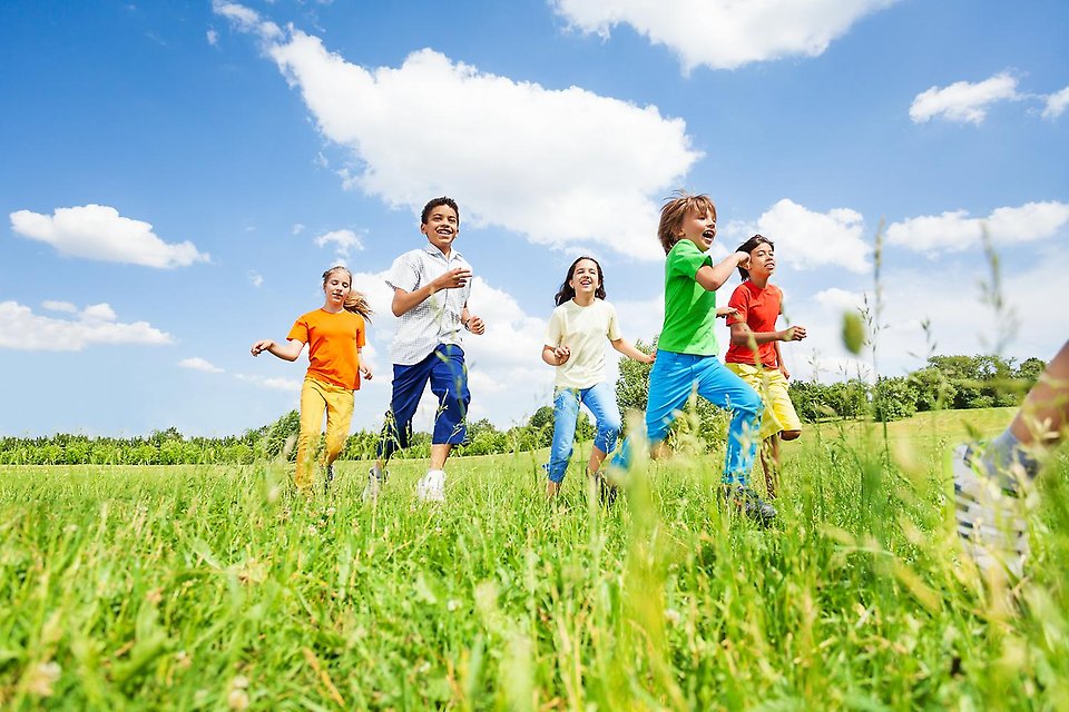 En färgglad bild på barn som glatt springer över en sommaräng
