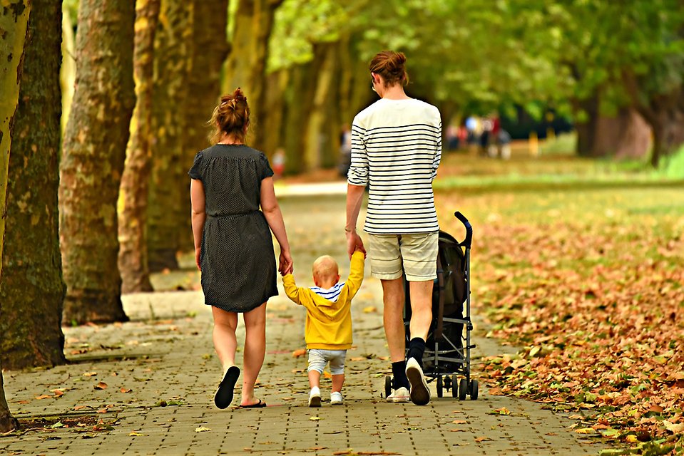 Mamma och pappa som går en promenad med sin bebis